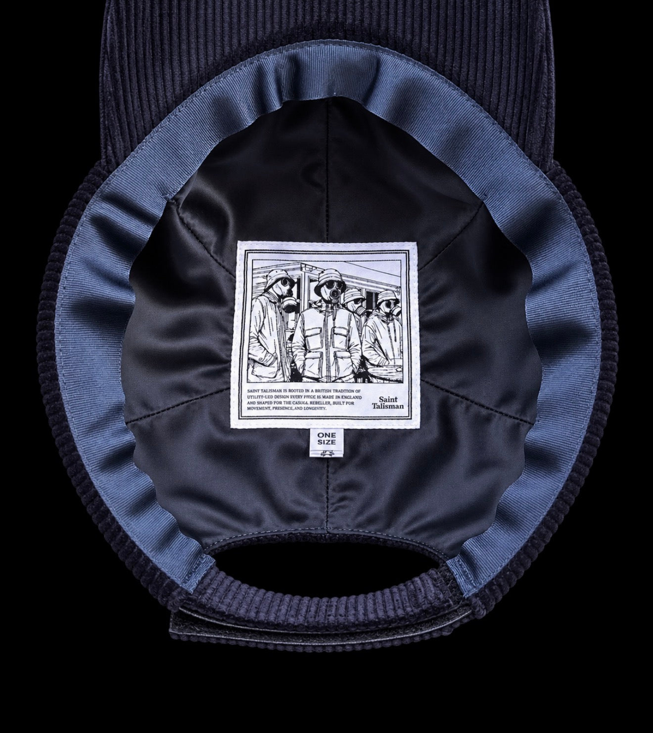 The inside of the Saint Talisman Cord Cap - Navy features a black-and-white illustrated label depicting people wearing hats, sewn onto the inner lining of this dark blue embroidered cap by the renowned British hat maker.