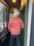 A person in a gray beanie and Danforth Embroidered Marinaio Sweatshirt - Marrone Storico, styled in British casual fashion, stands indoors by an open door with their back to the camera.